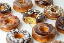 Various doughnuts with chocolate glaze, one with a bite taken out — Stock Photo