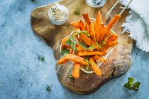 Spicy sweet potatoes fries with fresh herbs and salt flakes - foto de stock