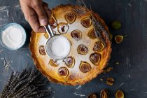 Розбризкування цукрового порошку на свіжоспеченому маскарпоне інжирний пиріг — стокове фото
