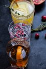 Verschiedene alkoholische Getränke mit Whisky, Bourbon, Wodka, Preiselbeeren, Orangen, Granatäpfeln, Rosmarin und Thymian — Stockfoto