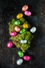 Chocolate eggs wrapped in bright foil surrounding an Easter nest — Stock Photo