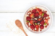 Porridge with fresh strawberries and strawberries, nuts, chocolate, mint and pomegranate seeds — Stock Photo