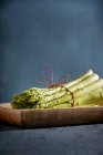 Um pacote de espargos verdes em um prato de madeira — Fotografia de Stock