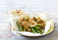 Asparagus with chicken breast and potatoes in parchment paper — Stock Photo