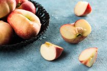 Peaches in basket and on rustic stone surface — Stock Photo