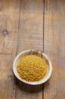Raw bulgur in wooden bowl over white background — Stock Photo