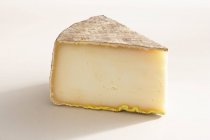 Pedaço de queijo de ovelha dura no fundo branco com sombra — Fotografia de Stock