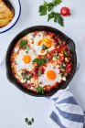 Shakshuka mit Tomaten, Paprika, Zwiebeln und Eiern in gusseiserner Pfanne zubereitet — Stockfoto