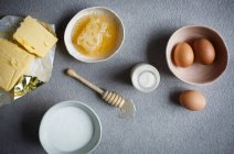 Mantequilla, miel, huevos y leche en la superficie de la mesa - foto de stock