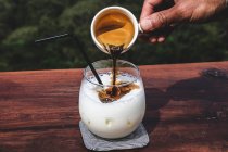 Verter el espresso en un café helado con leche - foto de stock