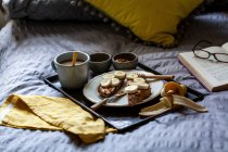 Desayuno en la cama con té, miel, mantequilla de maní y tostadas - foto de stock