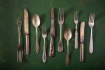 Vintage silver cutlery on green surface — Stock Photo