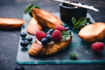 Toasted baguette slices with almond cream cheese, berries and mint — Stock Photo