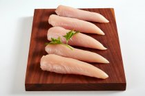 Filetes de pechuga de pollo crudos en una tabla de madera - foto de stock