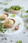 Peeled hemp seeds in a wooden bowl on a marble plate next to arugula leaves — Stock Photo