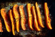 Oven-roasted pumpkin wedges on a baking tray — Stock Photo