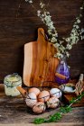 Свіжі яйця в металевому кошику. масло в банці і зеленій лозі — стокове фото