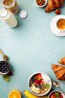 Breakfast with granola, yogurt, honey, fresh bananas, berries, chia seeds in bowl, coffee and croissants — Stock Photo