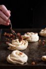 Cinnamon buns on a baking sheet, with a spoonful of cinnamon and brown sugar being placed on top — Stock Photo