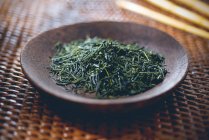 Green tea: tea leaves in a wooden bowl — Photo de stock