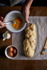 Un pan trenzado que se extiende con yema de huevo - foto de stock