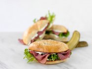 Bagel with roast beef, cream cheese, lettuce and pickles — Stock Photo