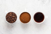 Kaffeetassen mit Kaffeebohnen, gemahlenem Kaffee und Filterkaffee — Stockfoto