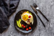 Тост с лососиной, авокадо, яичницей, помидорами, красным луком и крессом — стоковое фото