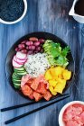 Hawaiian poke bowl with basmati rice, mango, raw salmon, avocado, radishes, cucumber and kalamata olives - foto de stock