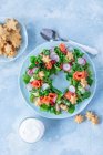 Salad in form of wreath with salmon, cucumber, radish, peas, corn and cheese cookies stars — Foto stock