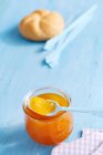 Jar of mango and vanilla jam with bread roll on background — Stock Photo