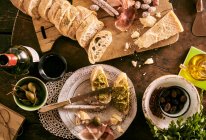 Bruschetta with pesto, mini salami, olives, Parmesan, olive oil, giant capers and red wine — Stock Photo