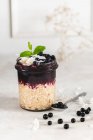 Oatmeal in jar with blackcurrants mousse, fresh berries, mint and coconut flakes — Stock Photo
