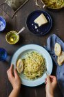 Spaghetti all'aglio, prezzemolo, peperoncino, olio e parmigiano, pane, parmigiano, olio d'oliva, acqua in un bicchiere, sale — Foto stock