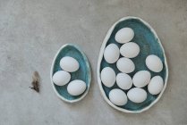 Egg-shaped ceramic plates with white eggs — Stock Photo