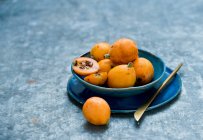 Plan rapproché de délicieux fruits Medlar dans un bol bleu — Photo de stock