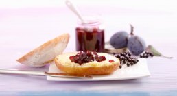 Figs and elderberries jam on bread roll half — Stock Photo