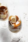Glasses with banana pudding - sliced bananas, wafer cookies, vanilla pudding, whipped cream and caramel sauce — Stock Photo