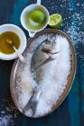 Sea bream in salt with olive oil and limes — Stock Photo