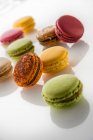 Different colorful macarons on white glass surface — Stock Photo