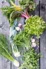 Varie verdure da giardino, lattuga ed erbe su una superficie di legno — Foto stock