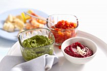 Bowls of various sauces for a fish fondue (exotic chutney, beetroot and horseradish dip, rocket and nut pesto) — Stock Photo