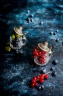 Красная смородина, черника и крыжовник в маленьких чашках — стоковое фото