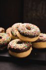 Donuts veganos horneados en horno con glaseado de chocolate negro y espolvoreos coloridos - foto de stock