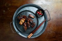 Caramelized pork ribs with chopsticks and dressing — Stock Photo