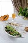 Ensalada con aguacate, papaya y rábanos y pasteles de pescado - foto de stock