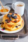 Blueberry pancakes served with honey and barley coffee — Stock Photo