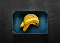 Plátanos en una caja de madera azul - foto de stock
