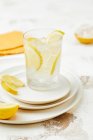Glass of drink with ice cubes and lemon wedges — Stock Photo