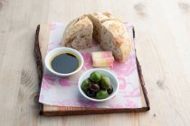 Pan blanco con queso, aceitunas y aceite sobre una tabla de madera - foto de stock